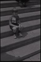 A child sits on the U.S. Capitol Building steps wearing a "Stop CBW" sign at a protest against chemical and biological warfare, Washington, D.C., 04 August 1969