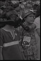 Two children, wearing a gas mask and helmet, stand among a crowd protesting chemical and biological warfare at the U.S. Capitol Building, Washington, D.C., 04 August 1969