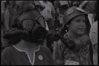 Children, wearing a gas mask and helmet, stand among a crowd protesting chemical and biological warfare at the U.S. Capitol Building, Washington, D.C., 04 August 1969