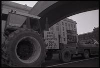 A truck tows a tractor, displaying a sign that reads "Broke Busted Discussed Need 100% Parity," along Independence Avenue SW during the first Tractorcade demonstration in Washington, D.C., 18 January 1978