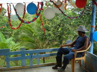Man in a cowboy hat sits on a porch during a during a birthday party, El Plátano, Panama