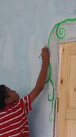 A boy paints a flower on a the mural at the library in El Plátano, Panama