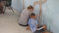 Rachel Teter and a boy paint images of tropical plants on the library mural, El Plátano, Panama 