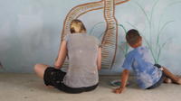 Close-up of Rachel Teter and a boy painting part of the library's mural, El Plátano, Panama 