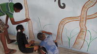 Children paint tropical plants on the mural at the community library, El Plátano, Panama 