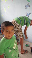 A boy smiles for the camera while another boys paints part of a mural at the new library, El Plátano, Panama 