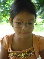A young girl wearing Rachel Teter's glasses upside down, El Plátano, Panama