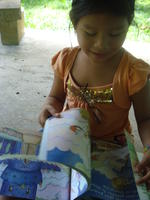 A young girl flips through a children's book in El Plátano, Panama
