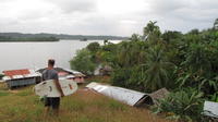 Man carries a surfboard and looks into the village below, Bocas del Toro, Panama
