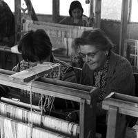 Peace Corps Volunteer Blanch Everhard sits next to a student at a loom during her weaving class at the Instituto de Educación Rural in Curicó, Chile
