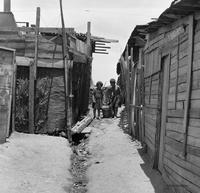 Children carrying a bucket through urban slums in the Población Colo Colo, Nueva Palena, Chile