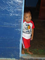 Boy leans on a doorway at a birthday party in El Plátano, Panama