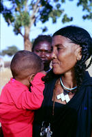 Grandmother wearing bone amulet holds grandson as daughter looks on