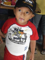 Boy licks cake icing from his mouth at a birthday party in El Plátano, Panama