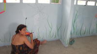 Young woman paints mural on the walls of a community library,  El Plátano, Panama