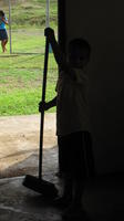Child sweeps in doorway at a community library,  El Plátano, Panama
