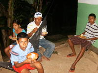 Man and children sit on porch eating slices of Gabina's birthday cake, El Plátano, Panama