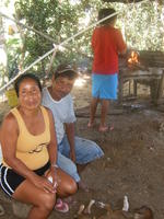 A man and woman sit by an outdoor oven at Gabina's birthday party in El Plátano, Panama