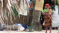 Kuna woman stands before palm trees holding a baby in San Blas, Panama