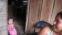 A young girl peers through a doorway while women prepare enyucado, El Plátano, Panama