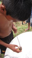 A boy removes a roasted marshmallow from a stick to make a s'more, El Plátano, Panama