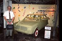 Man posing in front of "shootem" car at Yugo Next exhibition in Union Station, Washington, D.C.