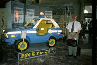 Man posing in front of "police" car at Yugo Next exhibition in Union Station, Washington, D.C.