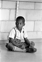 Young African-American boy sitting under a chalkboard at the Potomac School as part of the Adams-Morgan Community Council's Potomac Summer Project, McLean, Virginia