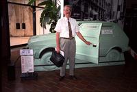 Man posing in front of "got 2 go" car at Yugo Next exhibition in Union Station, Washington, D.C.