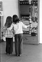 Young girls standing in front of a fun house mirror