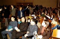 Members of the Chinese delegation sitting in auditorium in P.S. 75 in New York City with students raising their hands in the background