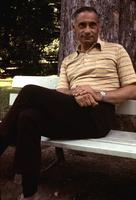 Herb Striner seated on a park bench wearing a striped shirt 
