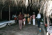 Man performing with band under thatched roof