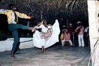 Dancers under thatched roof performing with band