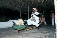 Woman performing bamboo dance under thatched roof