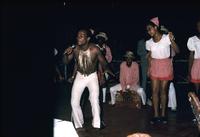 Man with microphone performing with dancers and band