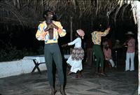 Dancers performing with band under thatched roof