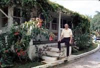 Herb Striner posing in front of white building covered in lush foliage