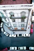 Aerial view displays a person standing by a building and cars parked alongside the sidewalk 