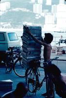 Young man loading or unloading a bike with newspapers, Hong Kong, China