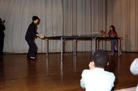 Female Chinese table tennis player hitting ball on stage with young girl in New York City