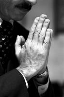 Alternate view of close-up of hands of man praying in church