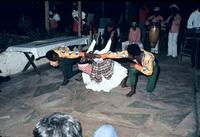 Female dancer performing limbo with male dancers using their arms in place of the bar