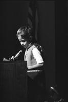 Young girl speaking into a microphone at a podium