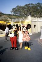 Mickey Mouse and Minnie Mouse stand with a visitor in Disneyland, Anaheim, California
